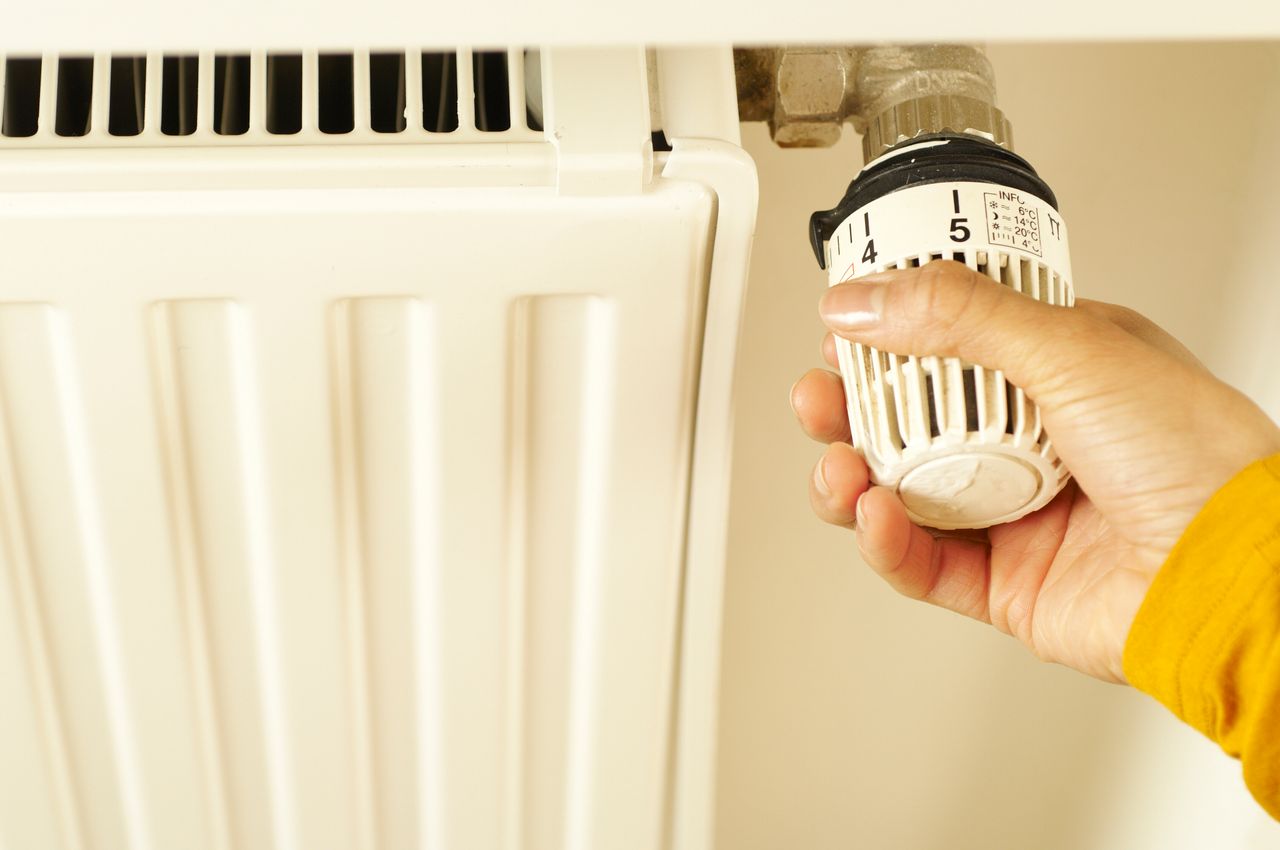 Mastering the First Impression: Your intriguing post title goes here Close-up of hand adjusting radiator thermostat to control home heating temperature.